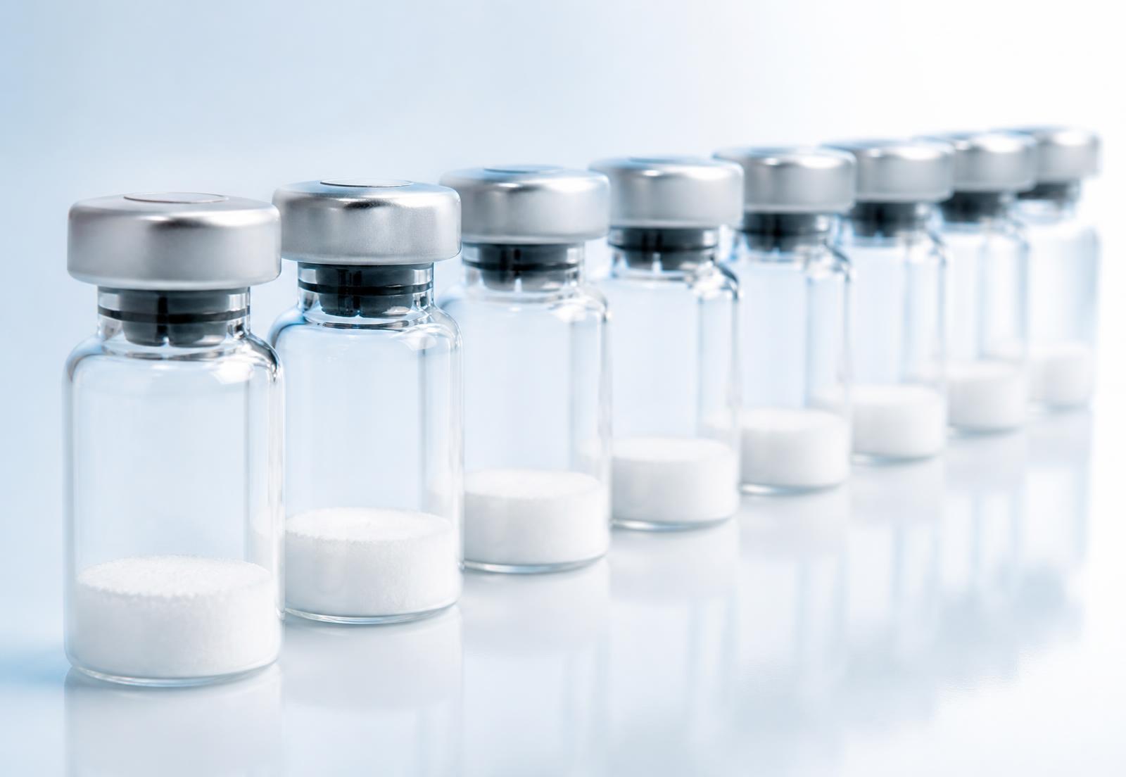 Row of lyophilised research peptide vials with crimped caps on a clean white background